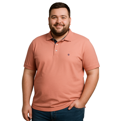 Hombre de complexión robusta sonriendo con polo Dubrovnik color salmón de la línea Tallas Extras, destacando el contraste azul marino en el cuello interno y logotipo bordado