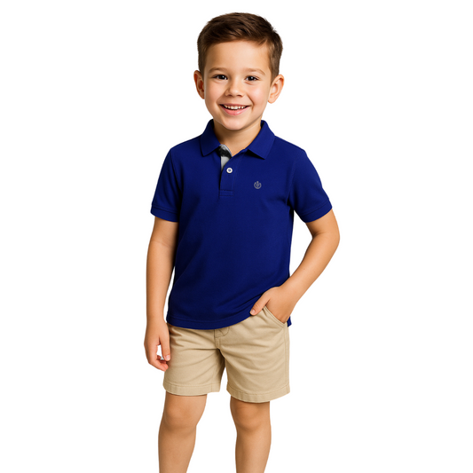 Niño sonriendo con un polo de manga corta en color azul marino con detalles grises en el cuello, combinado con bermudas beige, de la colección Dubrovnik Kids