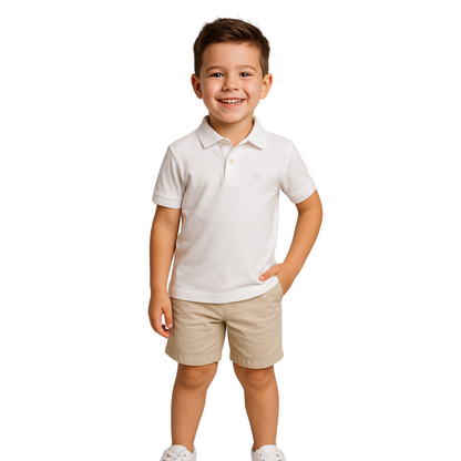 Niño sonriendo con un polo de manga corta en color blanco puro, combinado con bermudas beige, un básico esencial de la línea infantil de Dubrovnik