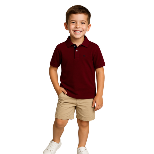 Niño sonriendo con un polo de manga corta en color granate y bermudas color beige, con fondo blanco, de la colección infantil de Dubrovnik