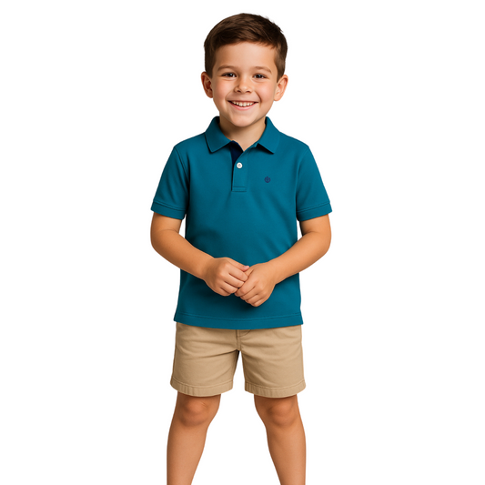 Niño sonriendo con las manos juntas, vistiendo un polo de manga corta en color turquesa oscuro con contraste azul marino en el cuello, de la línea infantil de Dubrovnik
