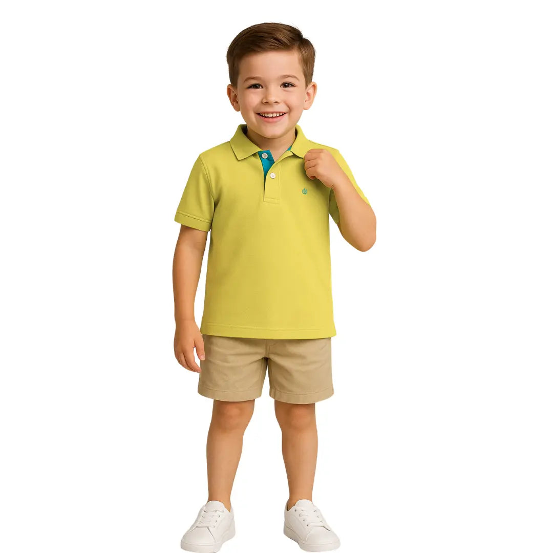 Niño sonriendo con un polo de manga corta en color verde lima con detalles turquesa en el cuello, combinado con bermudas beige, de la colección Dubrovnik Kids