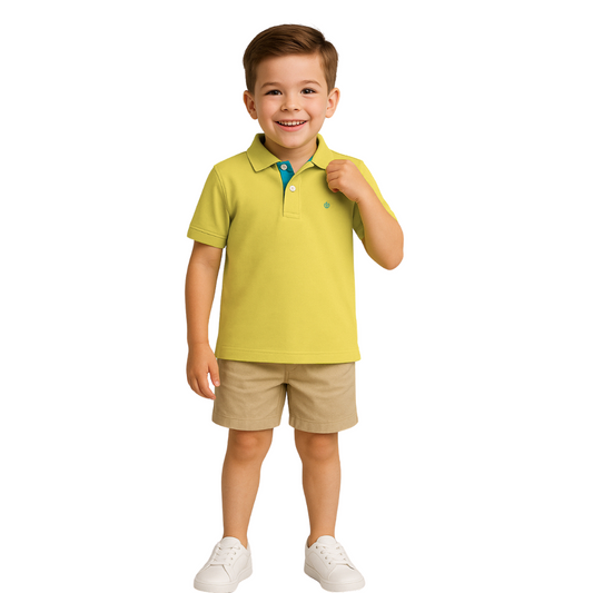 Niño sonriendo con un polo de manga corta en color verde lima con detalles turquesa en el cuello, combinado con bermudas beige, de la colección Dubrovnik Kids