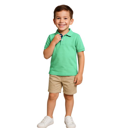 Niño sonriendo mientras sujeta el cuello de un polo de manga corta en color verde menta con contraste en azul marino en la carterita, combinado con pantalones beige, de la marca Dubrovnik