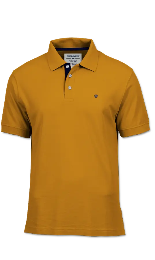 Polo de piqué Dubrovnik en color mostaza, destacando el contraste azul marino en el cuello interno, botones blancos de alta resistencia y escudo bordado en marino